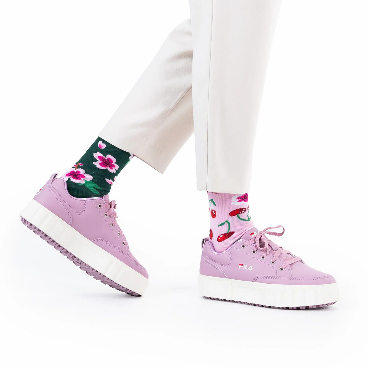 Person wearing pink sneakers and colorful socks on a white background