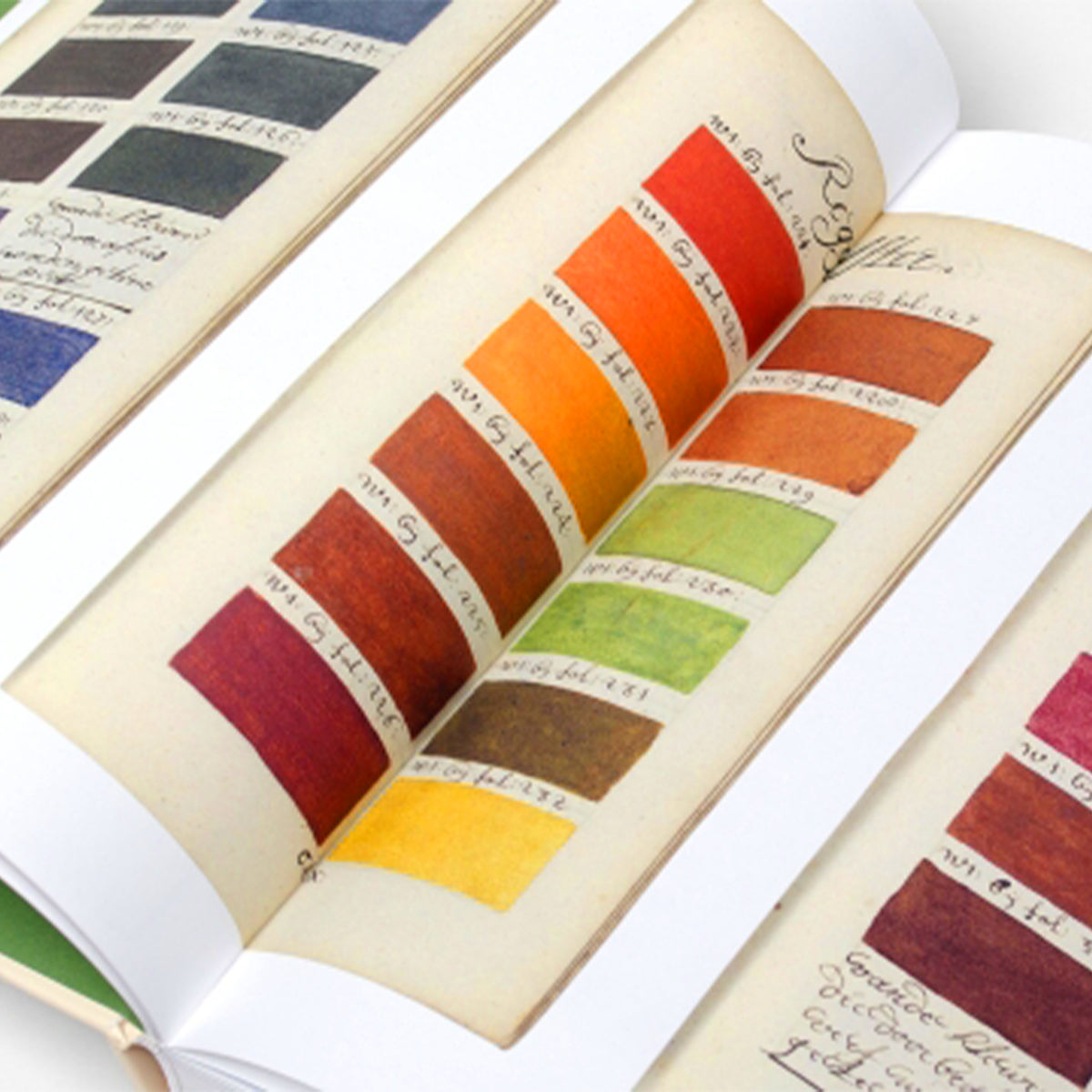 An open vintage-style color swatch book showing multiple painted color blocks and handwritten notes on aged cream pages.