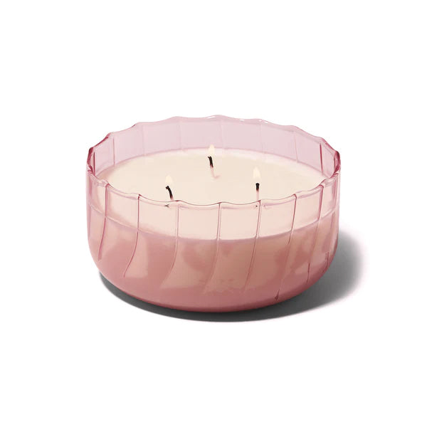 This ripple-edge, glass vessel, 12oz candle is designed to elevate tablescapes. Bring a vintage touch to your next dinner party with this subtle colored glass vessel. Top Notes: Peach, Bergamot. Middle Notes: Neroli, Linden Blossom. Base Notes: Amber, Coconut. Size: 12 oz 100% natural soy wax. Pink glass vessel.