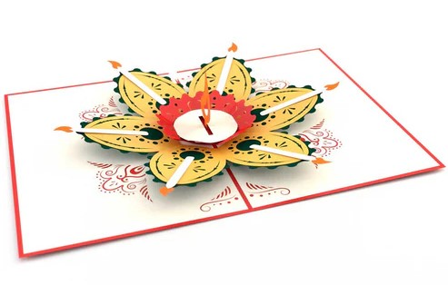 The front of this stunning pop-up Diwali card features an intricate, foil-embossed laser-cut lotus flower design. Once opened the card reveals a glorious 3D paper sculpture in the shape of a blooming lotus flower candle. Complete with paper candles and one large flame in the center this card embodies the significance of light in Hinduism.: 5" x 7".