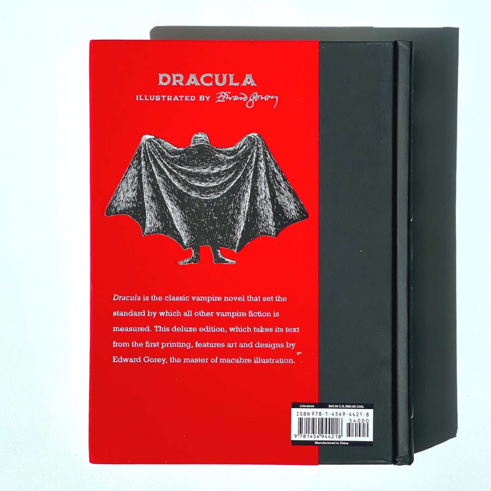A collector's edition of the book 'Dracula' by Bram Stoker, featuring a red and black cover with an illustration of a figure in a white dress with a large, dark winged figure behind them.