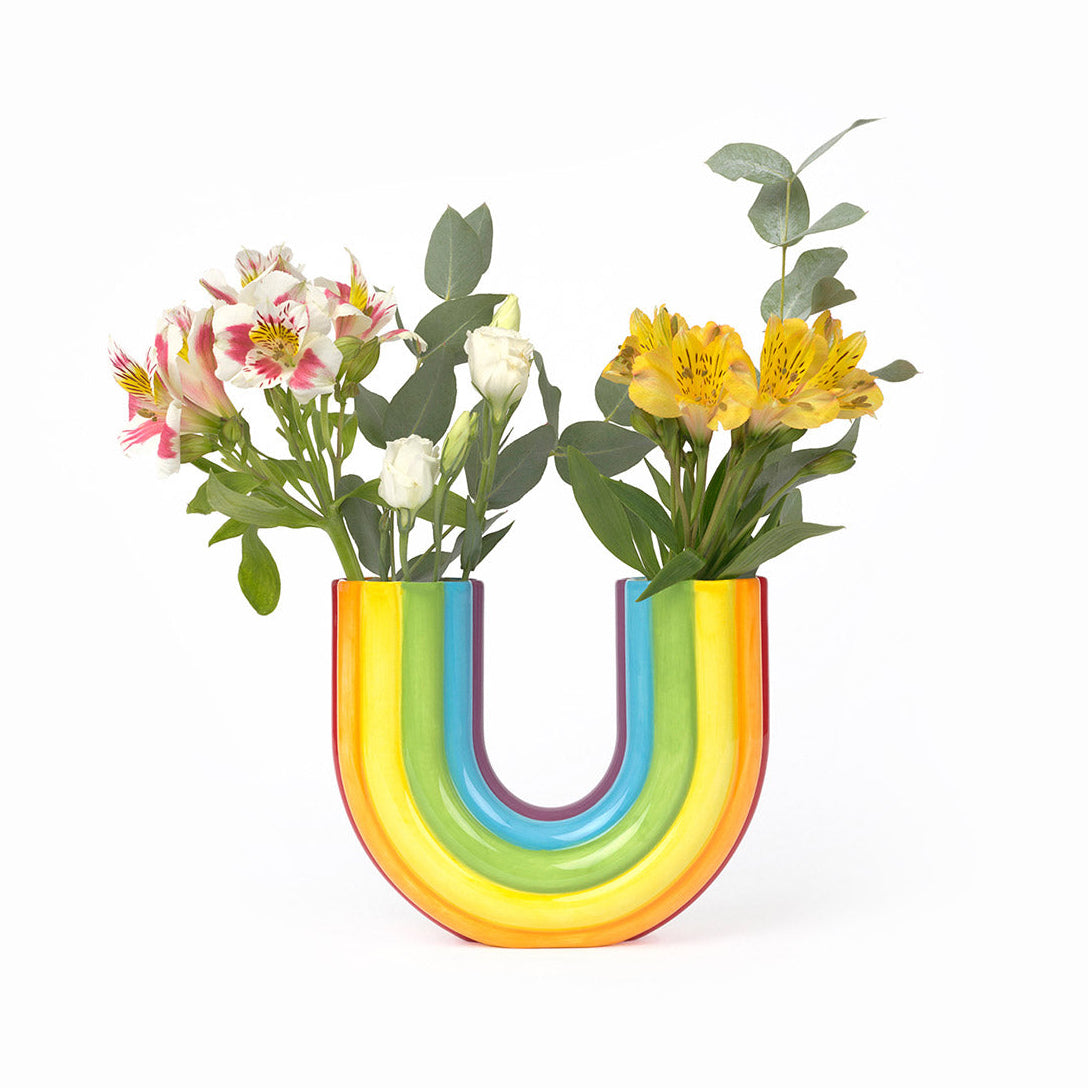 Colorful rainbow-shaped vase with flowers on a white background