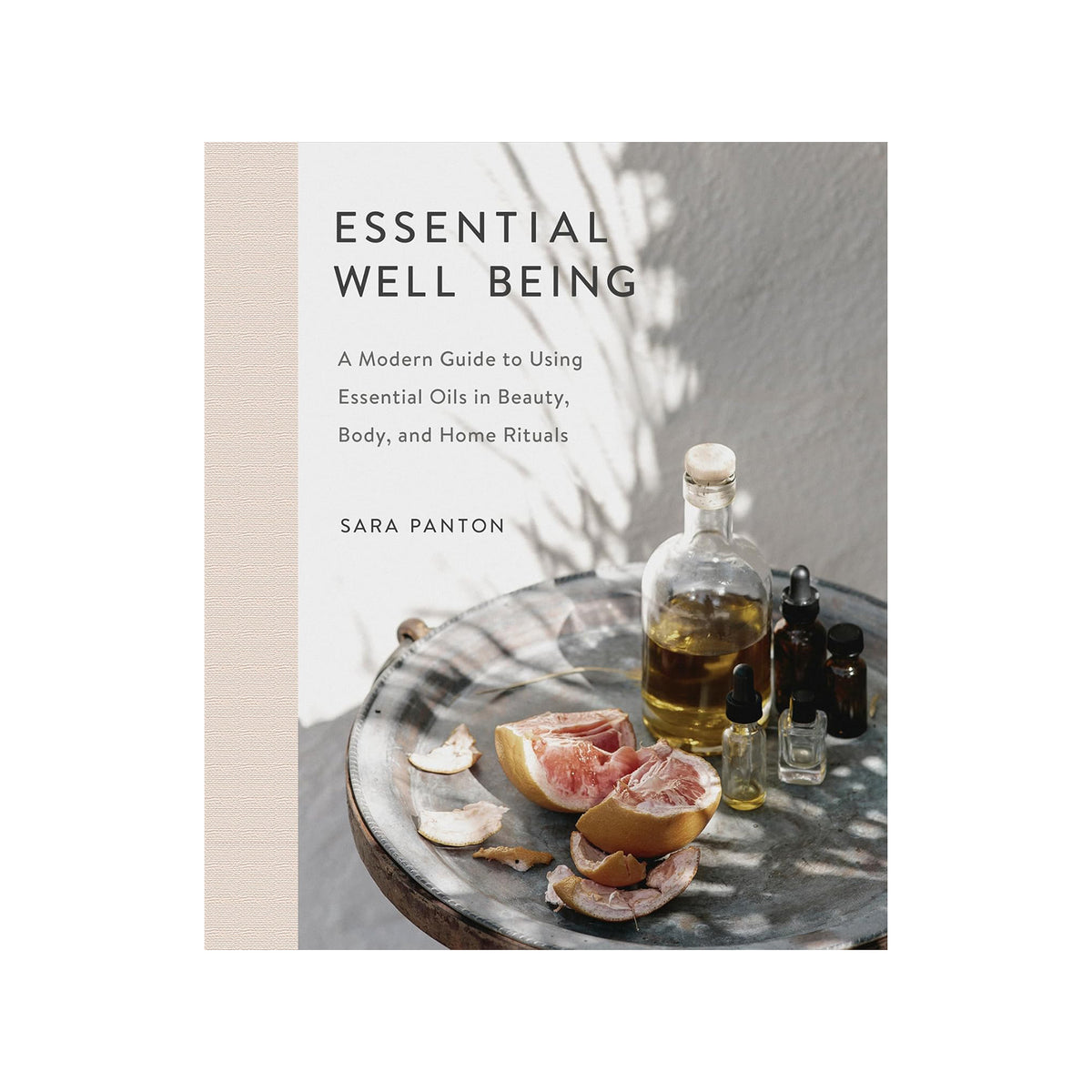 Book cover of 'Essential Well Being' by Sara Panton with essential oils and fruits on a table.