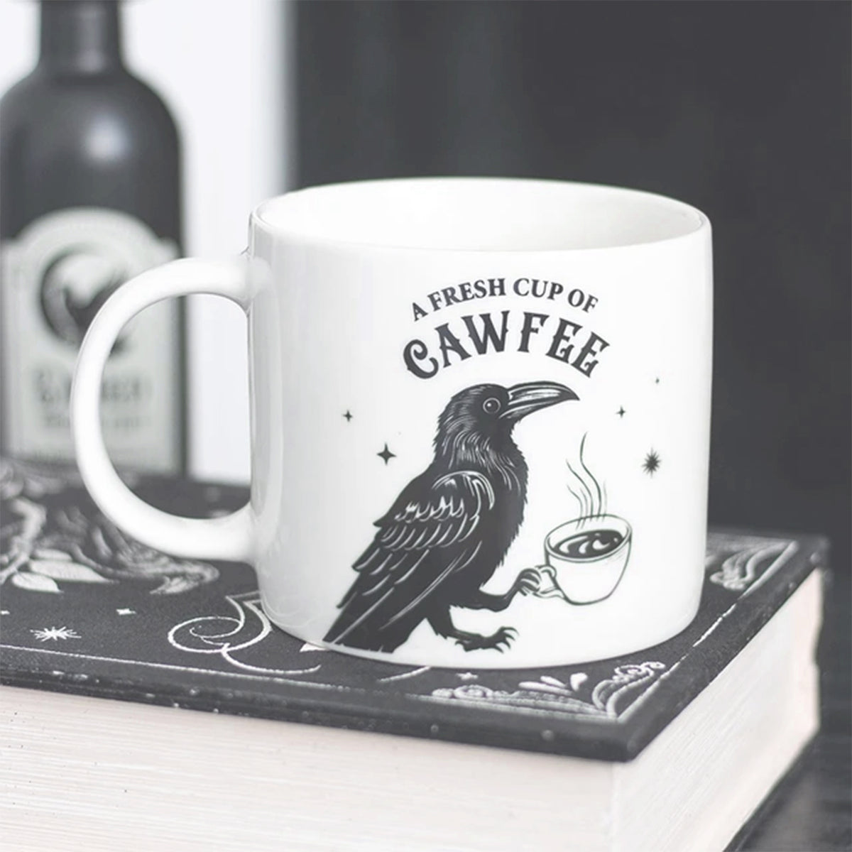 Mug with a crow design and text 'A Fresh Cup of Cawfee' on a black and white surface.