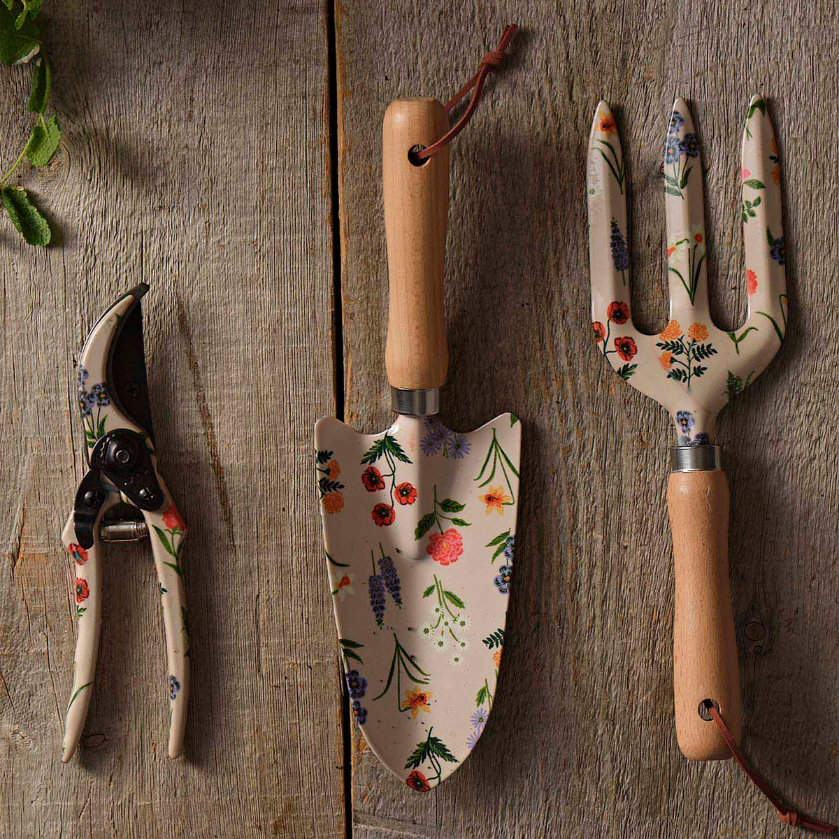 Set of gardening tools with floral handles on a wooden surface