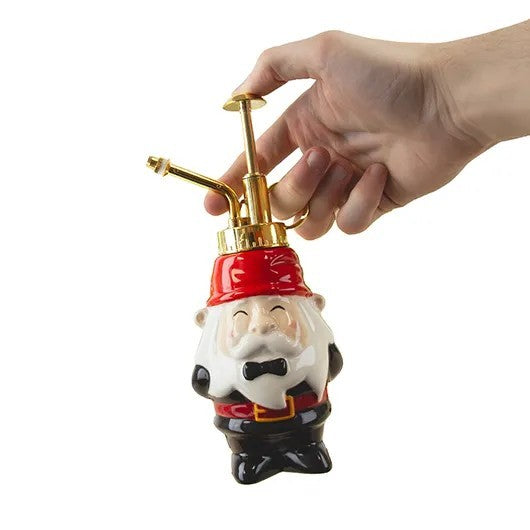 Hand holding a gnome-shaped plant mister on a white background