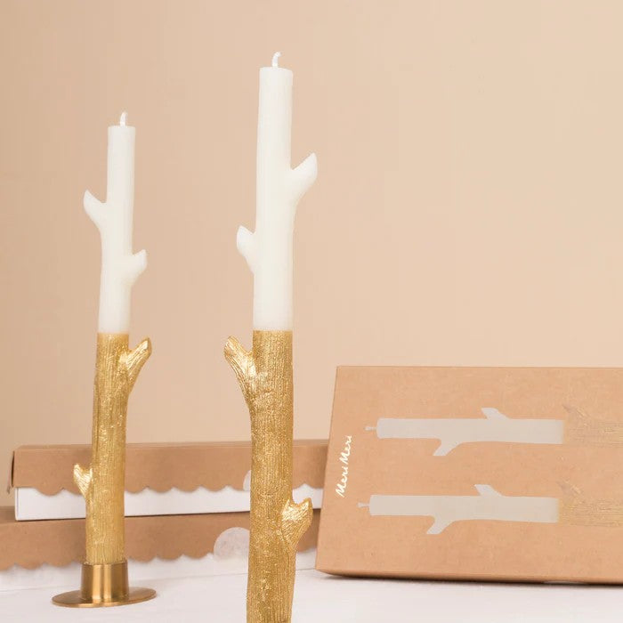 Gold candle holders with white candles on a beige background