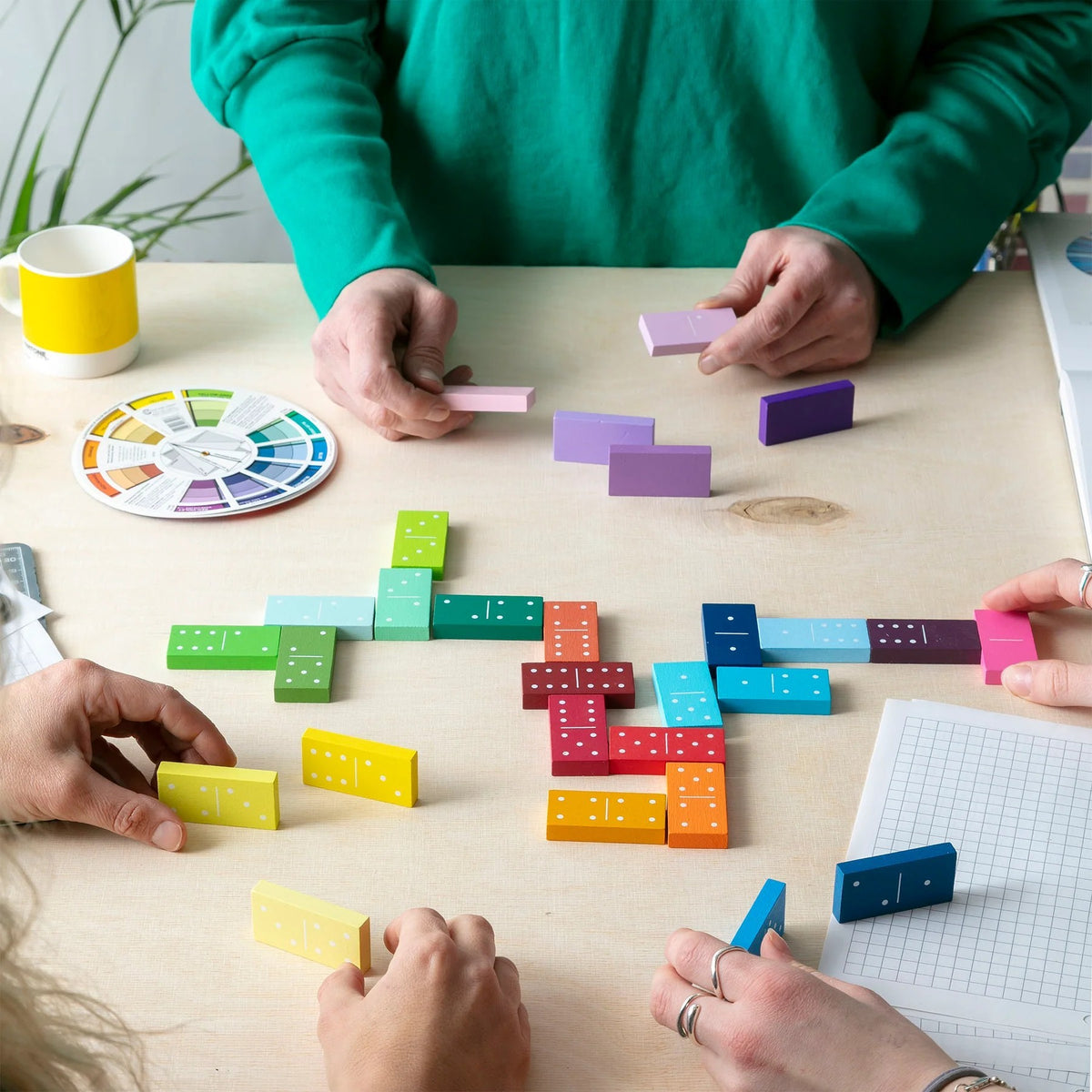 Colorful dominoes on a table with people arranging them