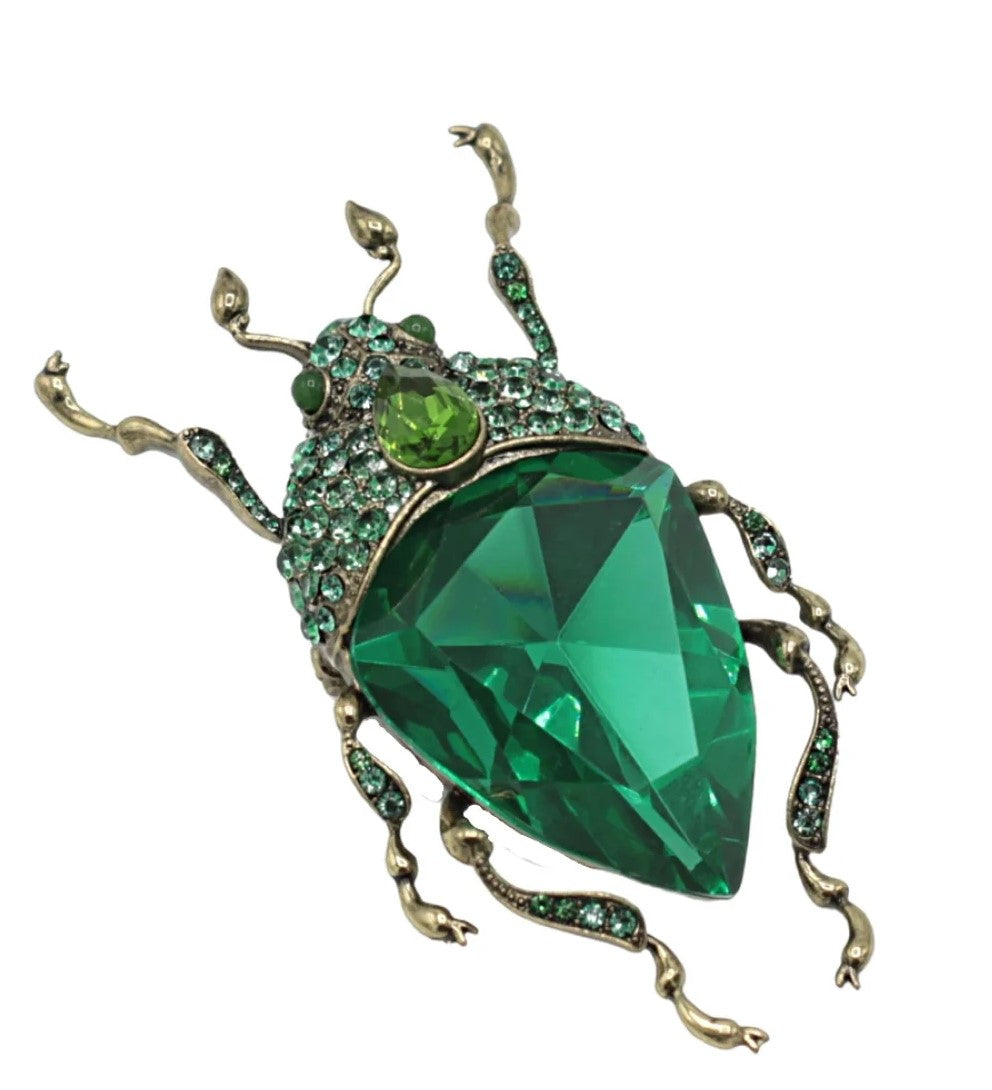 If the Emerald City had bugs, they would look like this! This green bug brooch has a multi-faceted green glass body and crystal encrusted legs and head, all on an antique gold base. Wear on a solid color outfit for a pop of interest and sparkle. Brass with antique gold plating, glass, crystal. Dimensions: 2.25" x1.5".