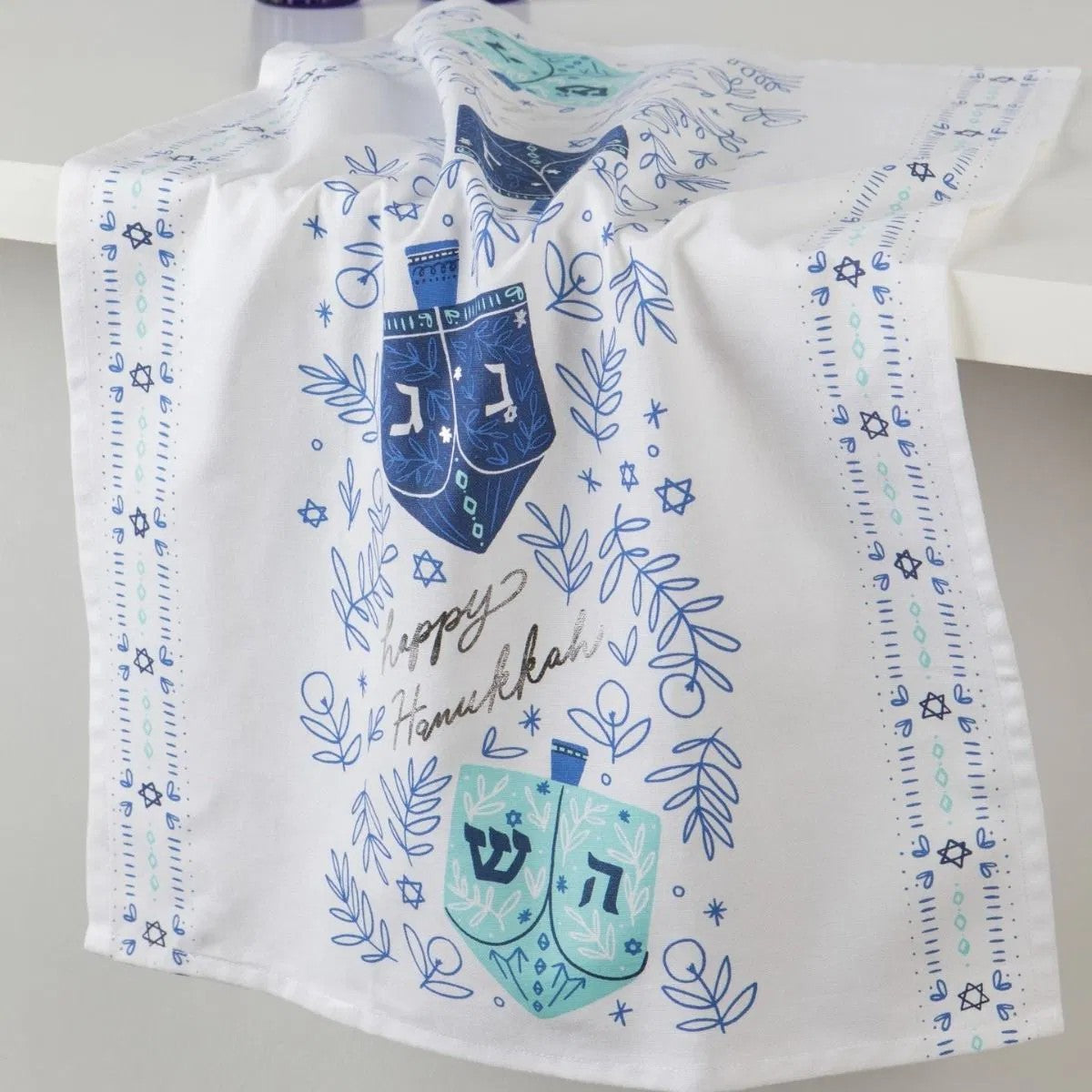 Decorative tea towel with blue dreidels and Star of David on a white background
