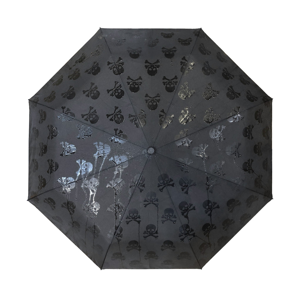 A classic black umbrella, with a dark hidden secret! As it rains, this black umbrella, is transformed into a pattern of black-on-black skulls... like magic. The print is created with a “secret” ink that is only revealed when wet. Lightweight, portable, super-tough and durable. 39" diameter when open.