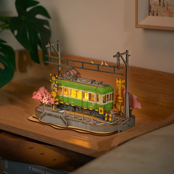 This delightful DIY wooden puzzle features a charming Japanese tram, beautifully set on a track surrounded by blooming Sakura trees.

The tram is filled with miniature wooden passengers, capturing a serene and nostalgic atmosphere on a spring day in Japan. As you assemble this puzzle, you'll bring to life a picturesque scene, where the tram seems to glide gently through a landscape of cherry blossoms, evoking the tranquil beauty of Japanese culture.
