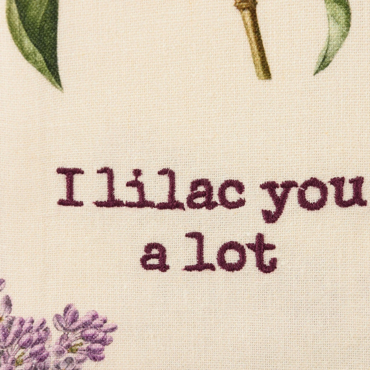 Text 'I lilac you a lot' with floral elements on a beige background