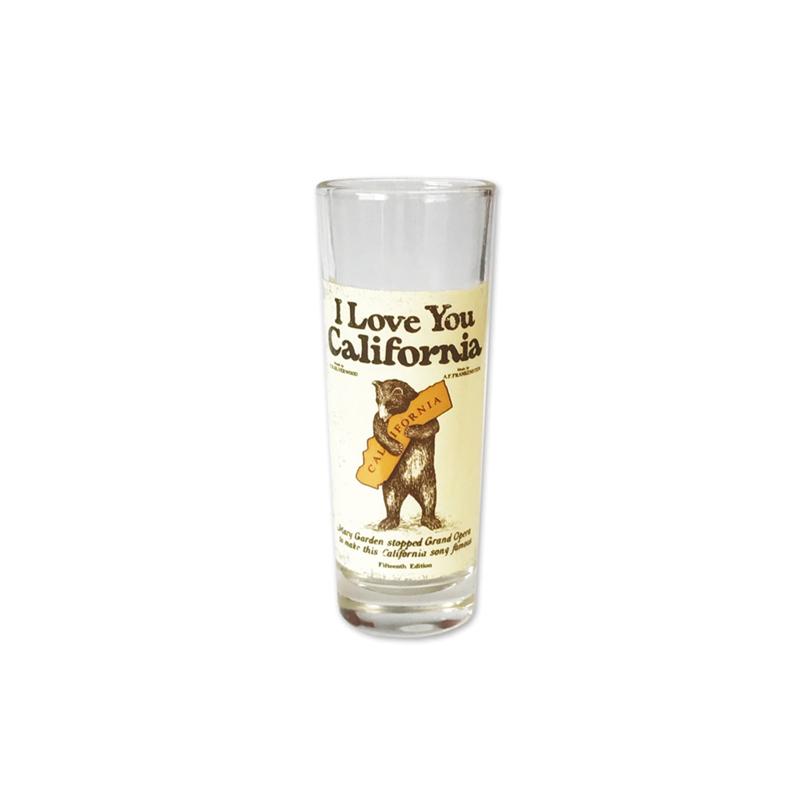 A clear glass shot glass featuring a vintage-style cream label with the text 'I Love You California' and an illustration of a bear holding a sign that reads 'I Love You California'.