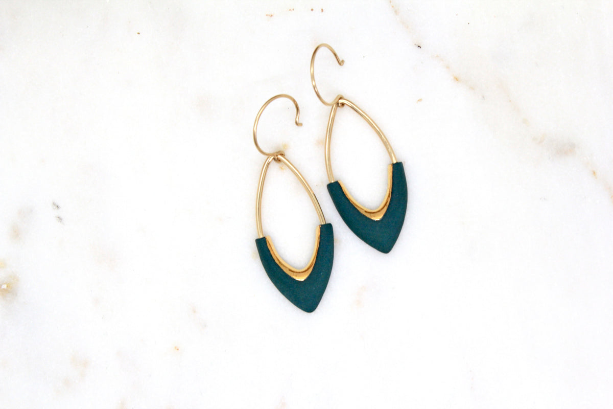 Gold and teal earrings on a light background
