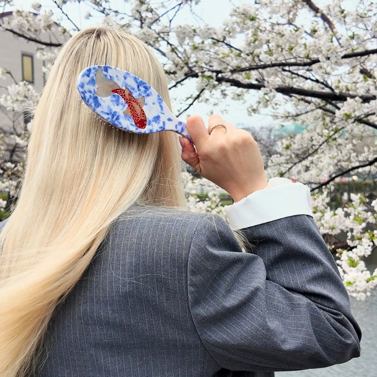 This gorgeously striking hairbrush features a design with a vibrant Koi carp swimming in beautiful blue waters. It is finished with hand-painted details and is crafted in small batches.