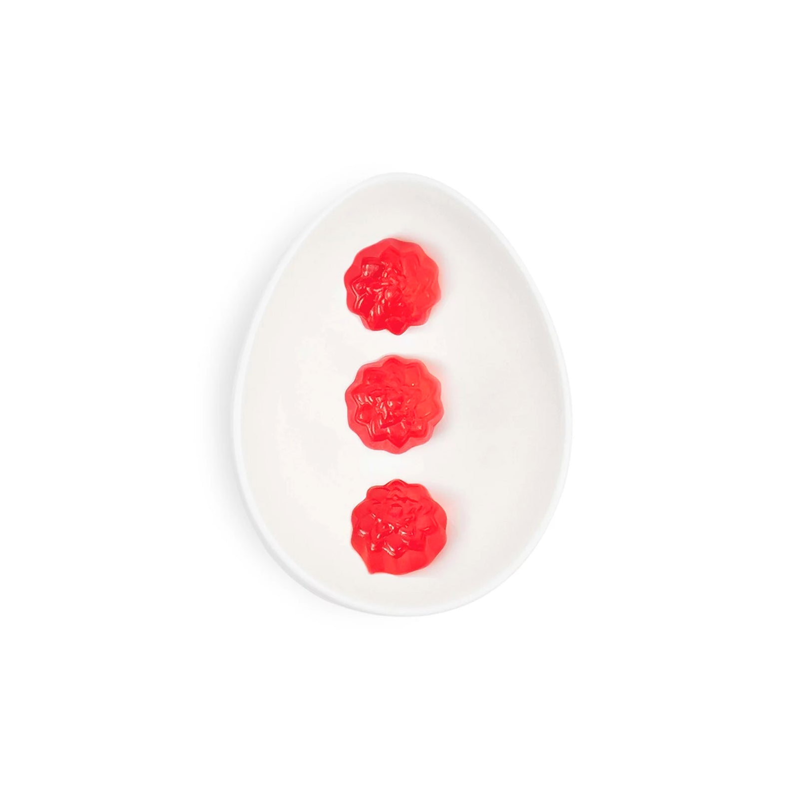 Red gummy candied shaped like flowers in a clear cube container on a white background