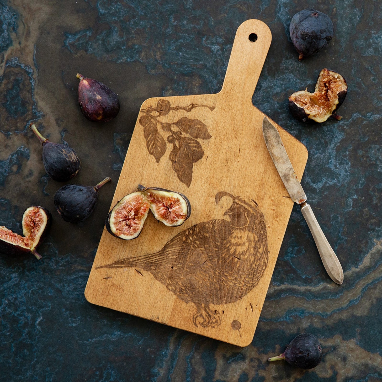 This engraved maple wood serving board features an exquisitely detailed quail. With a handle and hole for wall hanging, this versatile board could be used practically or as a decor piece. A great gift for any bird-watching friend. Dimensions: 11" x 6" x 0.5" Material: maple wood. Made in Vermont.