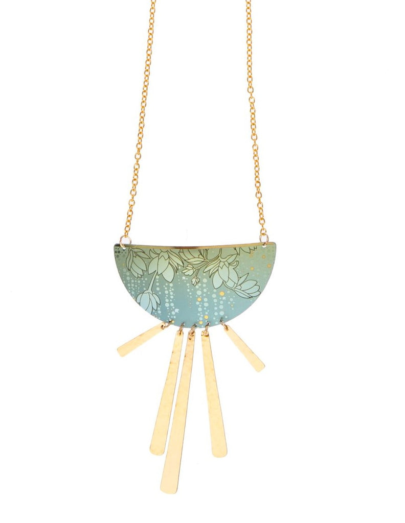 A sizable half-moon pendant serves as a velvet-sheen niobium canvas, patterned in a cascading magnolia flower motif and culminating in a dancing line of hand-hammered golden fringe. Gold overlay chain. Bohemian glass. Adjustable: 16-34" long Pendant: 3" l. x 2" w.