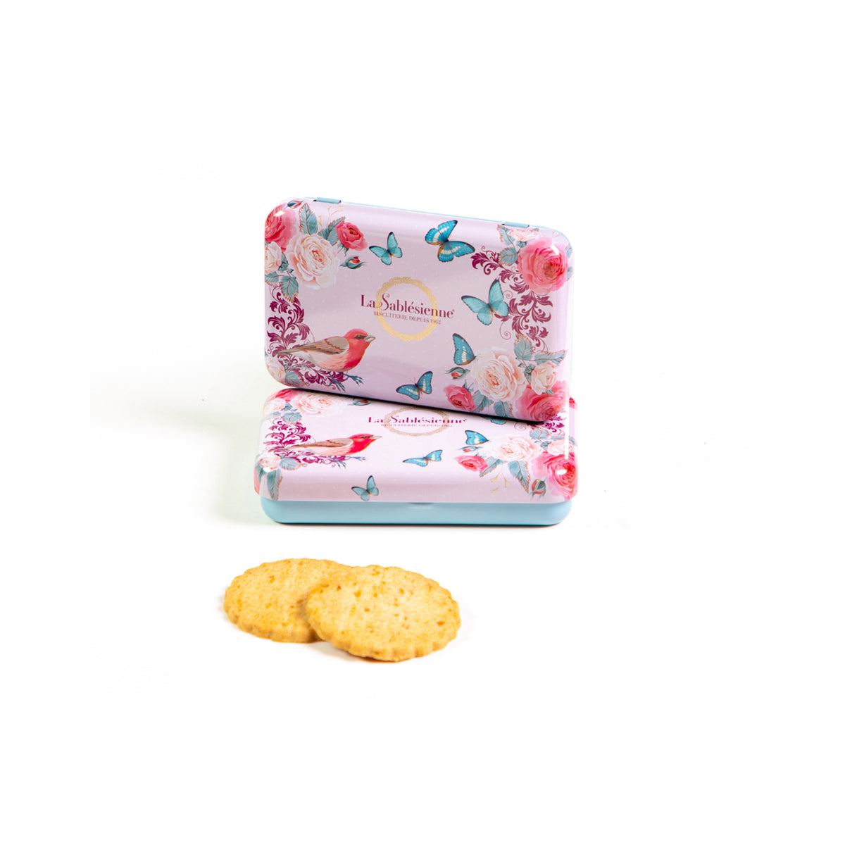 Two rectangular pink biscuit tins with a floral and butterfly pattern, stacked with two round golden biscuits in front, on a white background. The brand name 'La Subtilité' is visible on the tins.