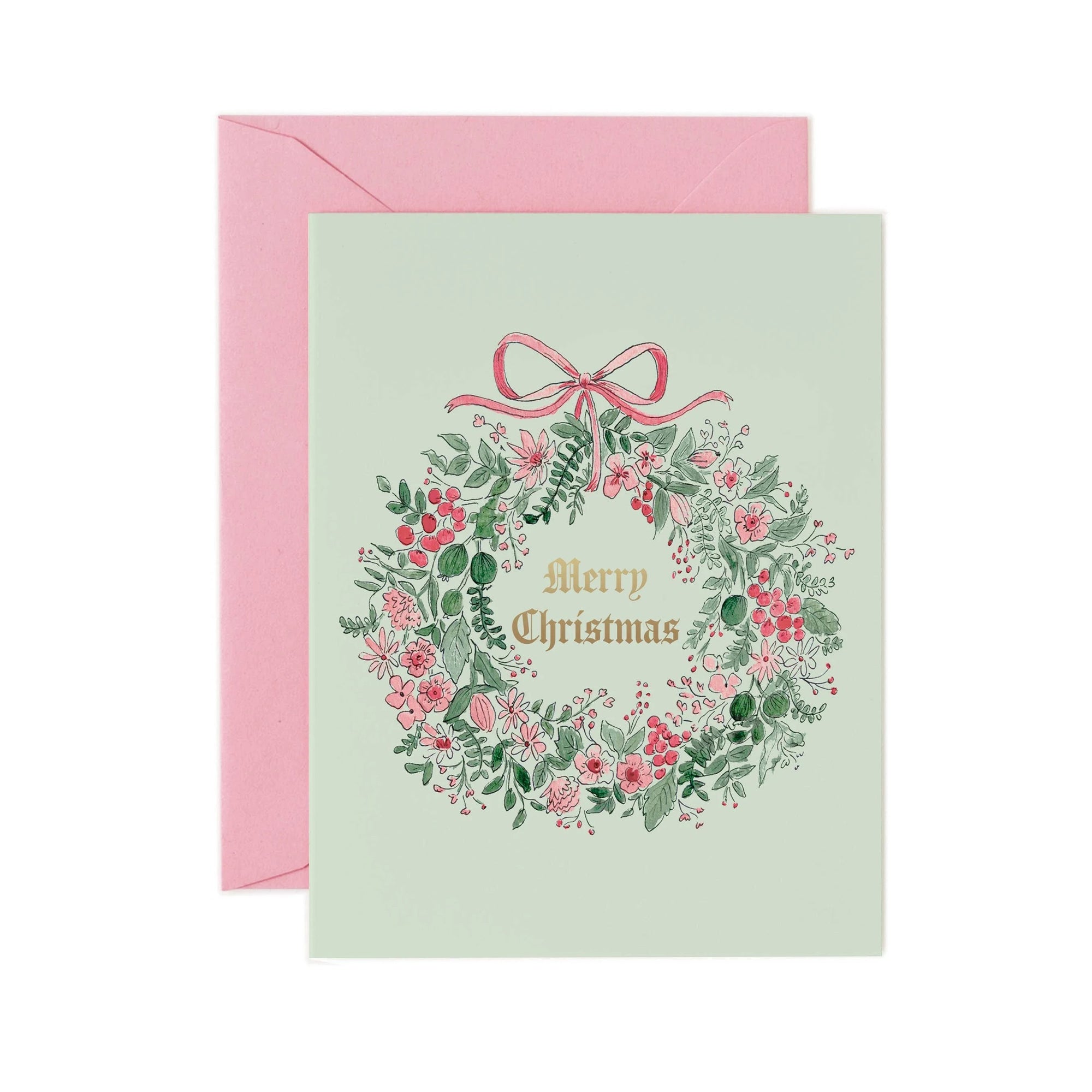 Christmas card with floral wreath and pink bow on a light green background, accompanied by a pink envelope.