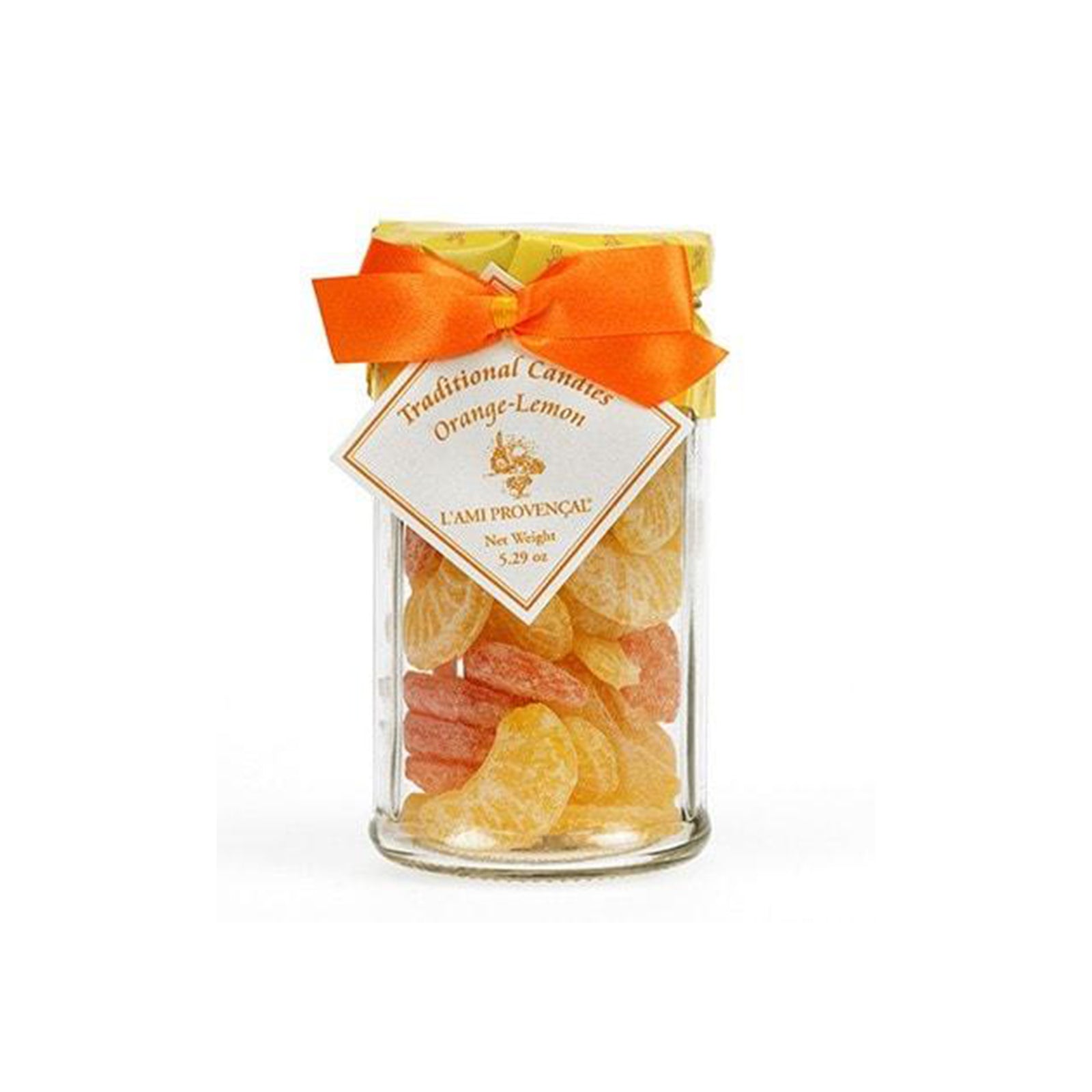 A clear glass jar filled with orange and yellow dried citrus candies, tied with a bright orange ribbon and a diamond-shaped label that reads 'Traditional Candies Orange-Lemon L'ami Provençal'.
