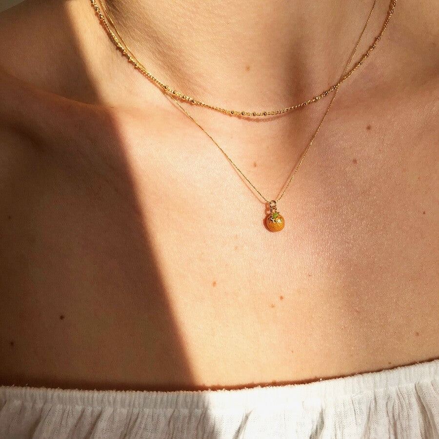 This cute and quirky pendant necklace is the perfect piece of fruity jewelry for adding to your collection or giving as a sweet gift. Featuring a tiny orange shaped pendant, suspended from a fine chain which fastens via lobster clasp and extender links. 18ct gold plated brass, enamel.