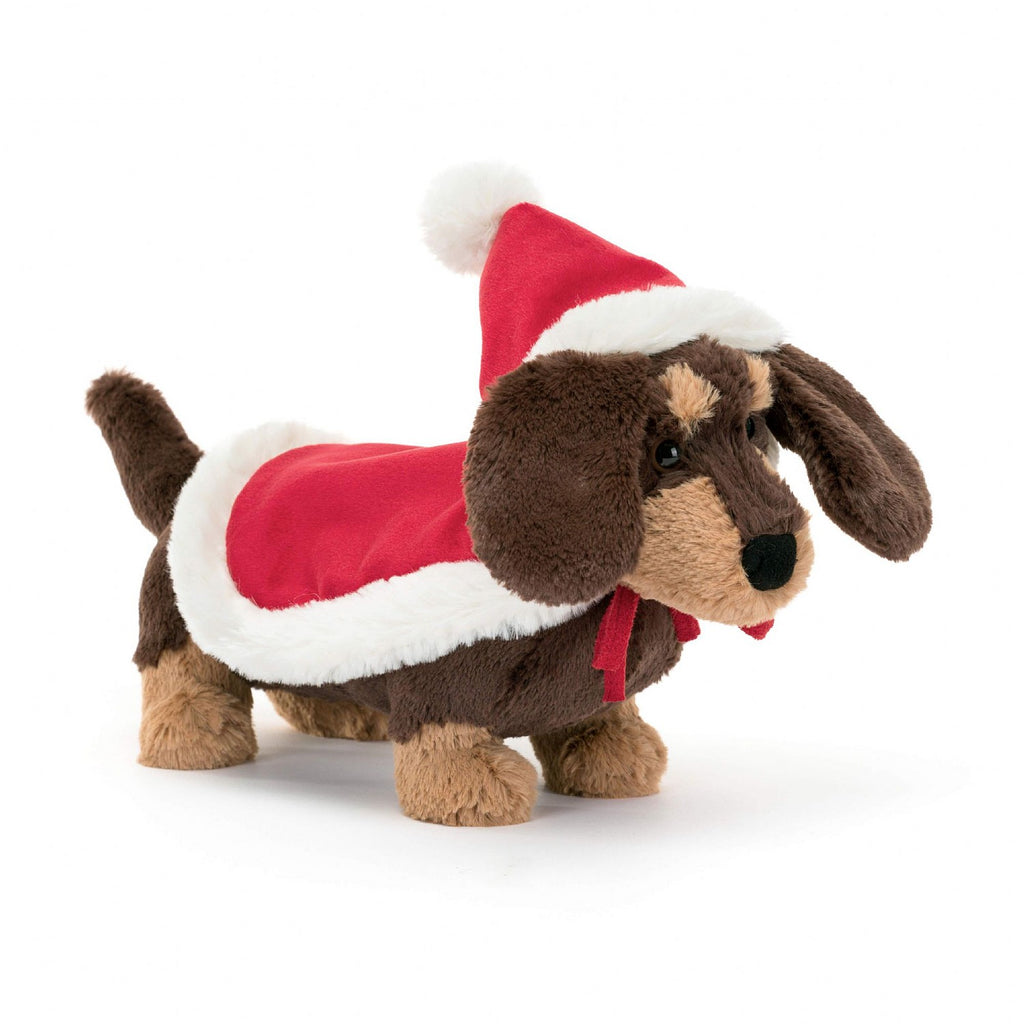 Winter Warmer Otto Sausage Dog is setting new trends for holiday fashion! This floppy-eared pup wears a red hat-and-cape combo, with a fleecy trim and bobble pompom, which fastens on with a red ribbon tie. It goes so well with Otto's cocoa fur, splashed with caramel patches! Dimensions: 6" x 3" Suitable from birth.