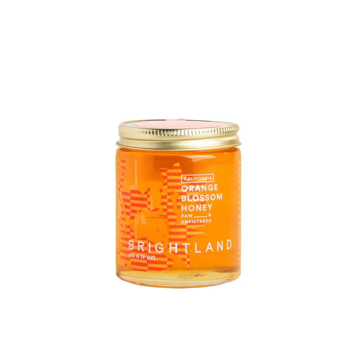A glass jar of Brightland California Orange Blossom Honey with a gold metal lid, set against a solid white background.