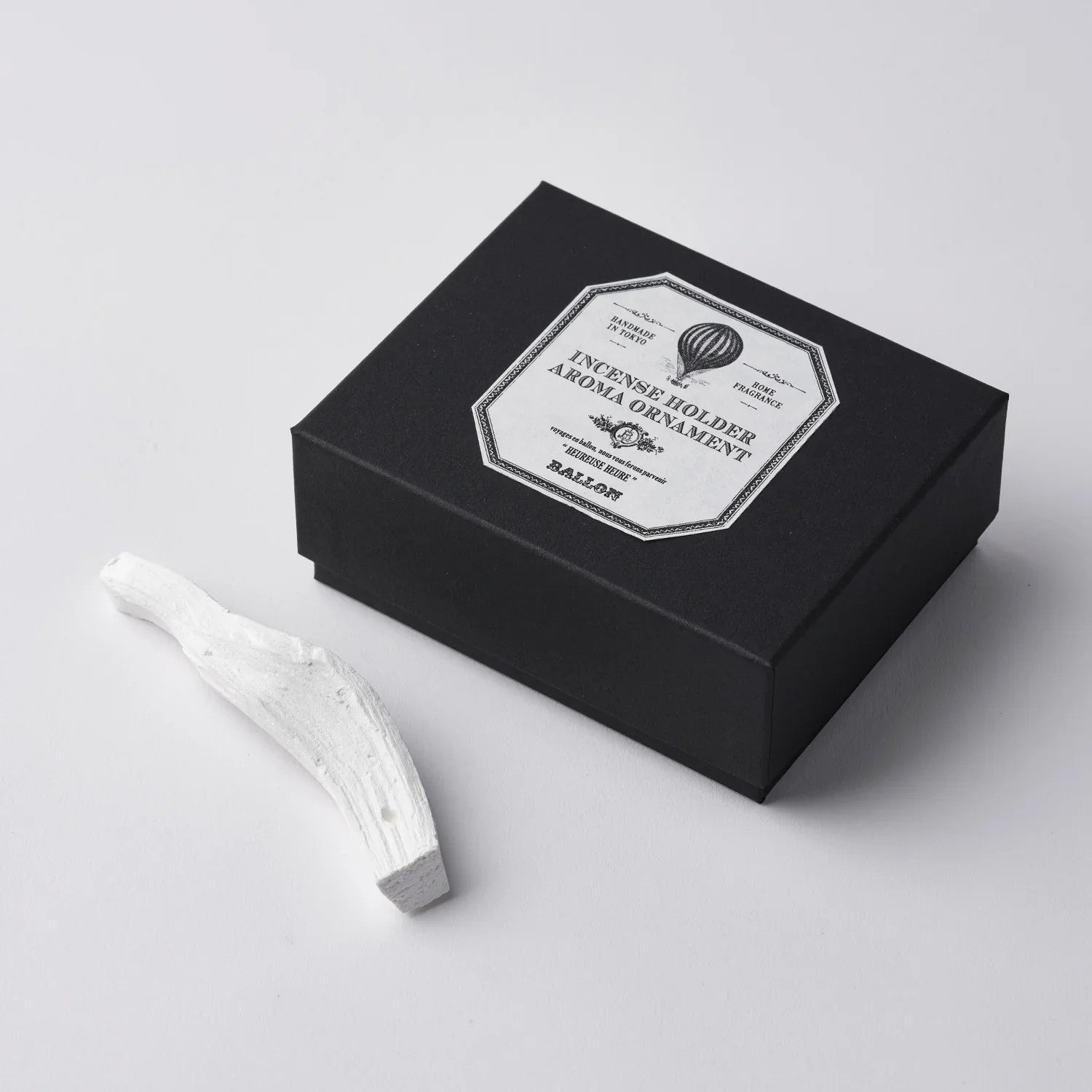 White branch-shaped incense holder with an incense stick on a white background