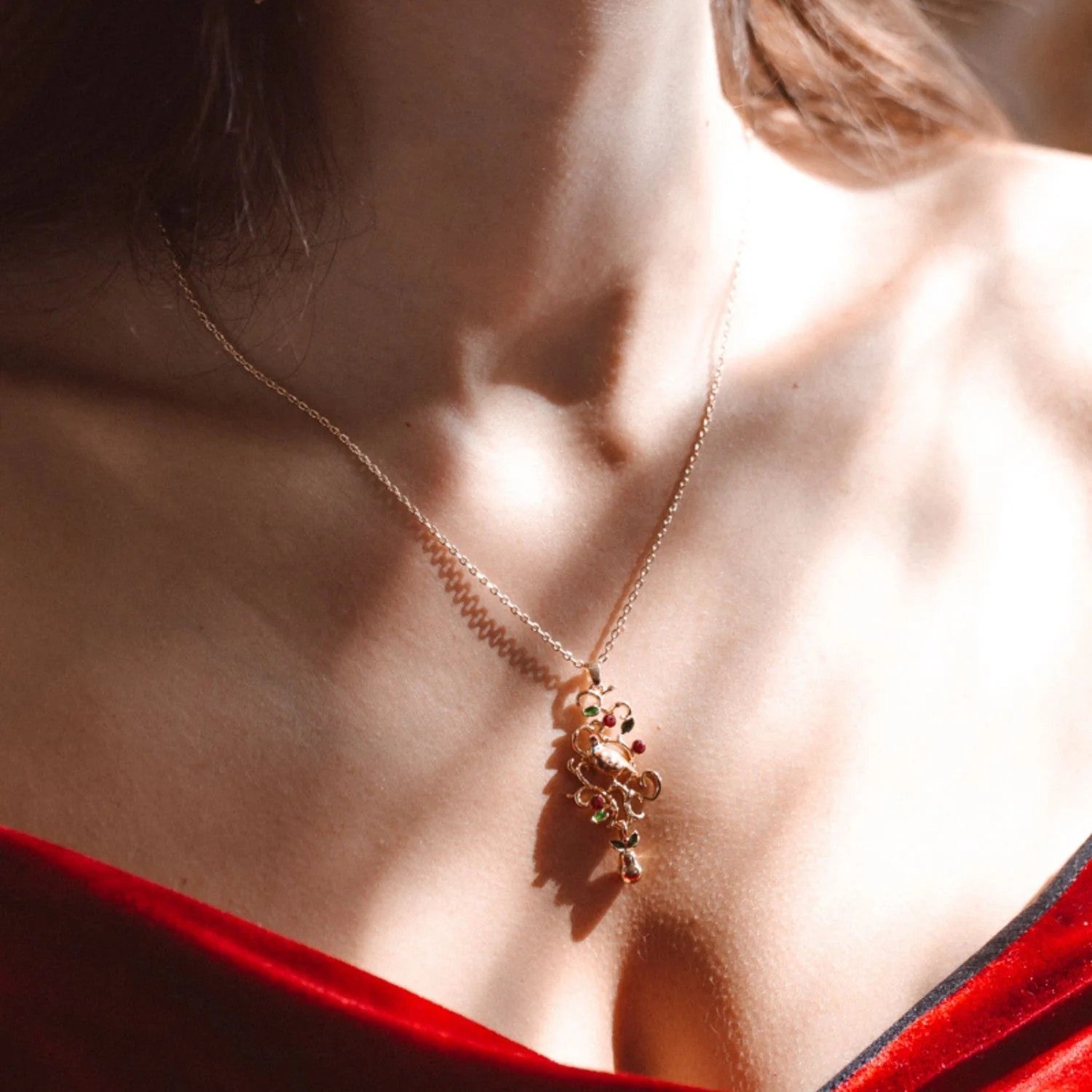 Gold necklace with a colorful pendant on a white background