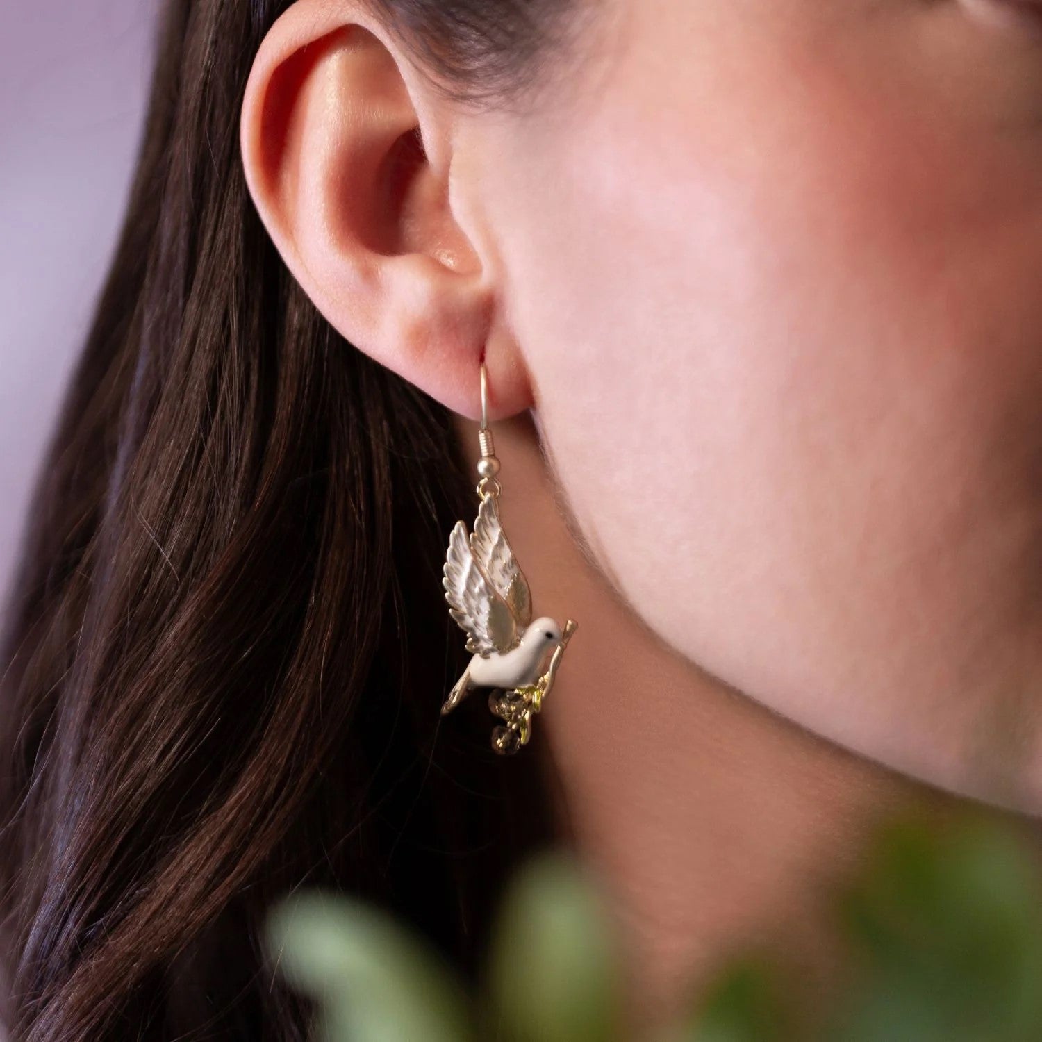 These delightful dangle earrings feature a delicate and intricately designed peace dove, crafted with precision and adorned with enchanting enamel detailing.  Materials: Gold plated brass, enamel, glass beads. Dimensions: 1.2" x 0.75". Hook fastening.