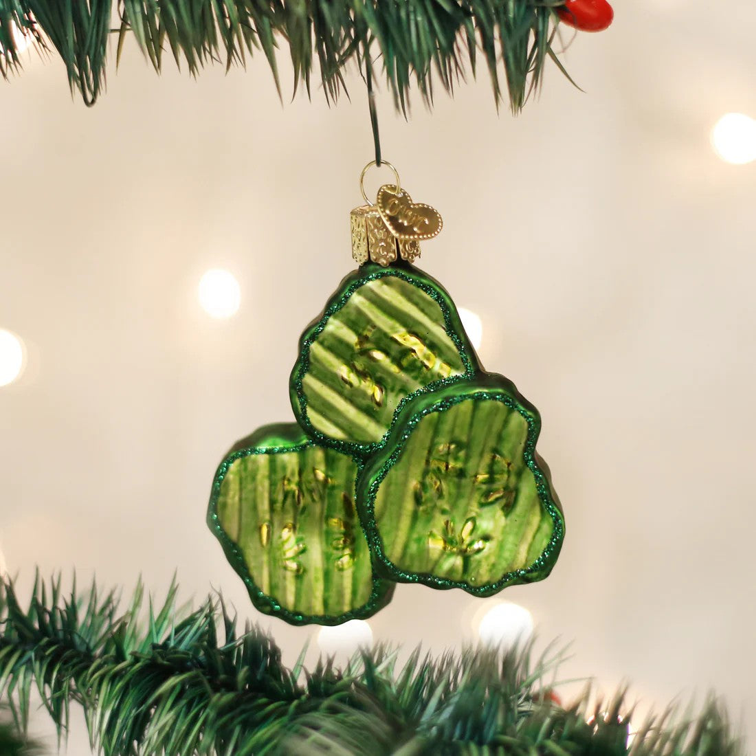 Decorative glass ornament shaped like pickle slices on a white background