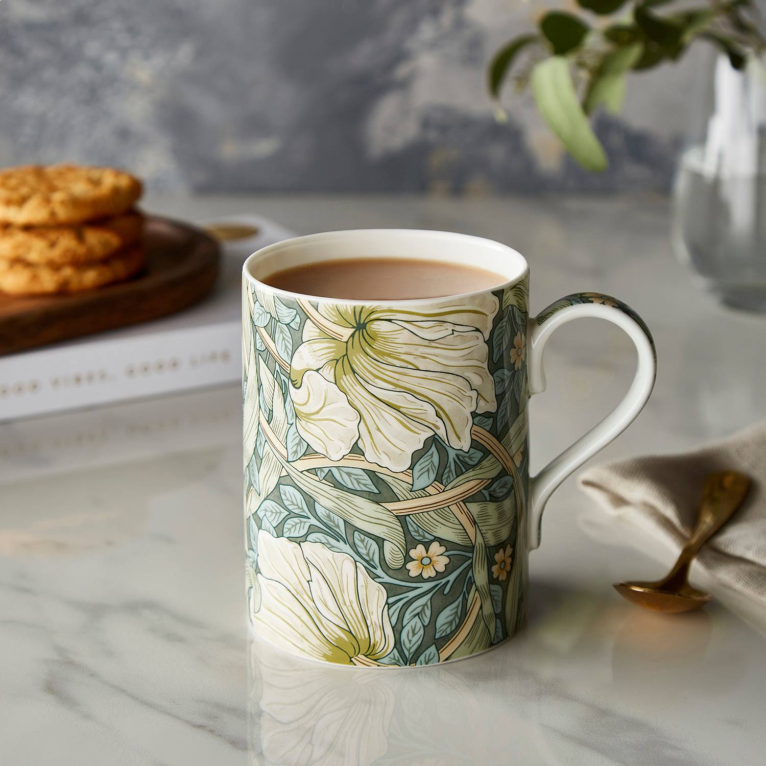 Mug with William Morris 'pimpernel' floral pattern design in green and cream on a white background