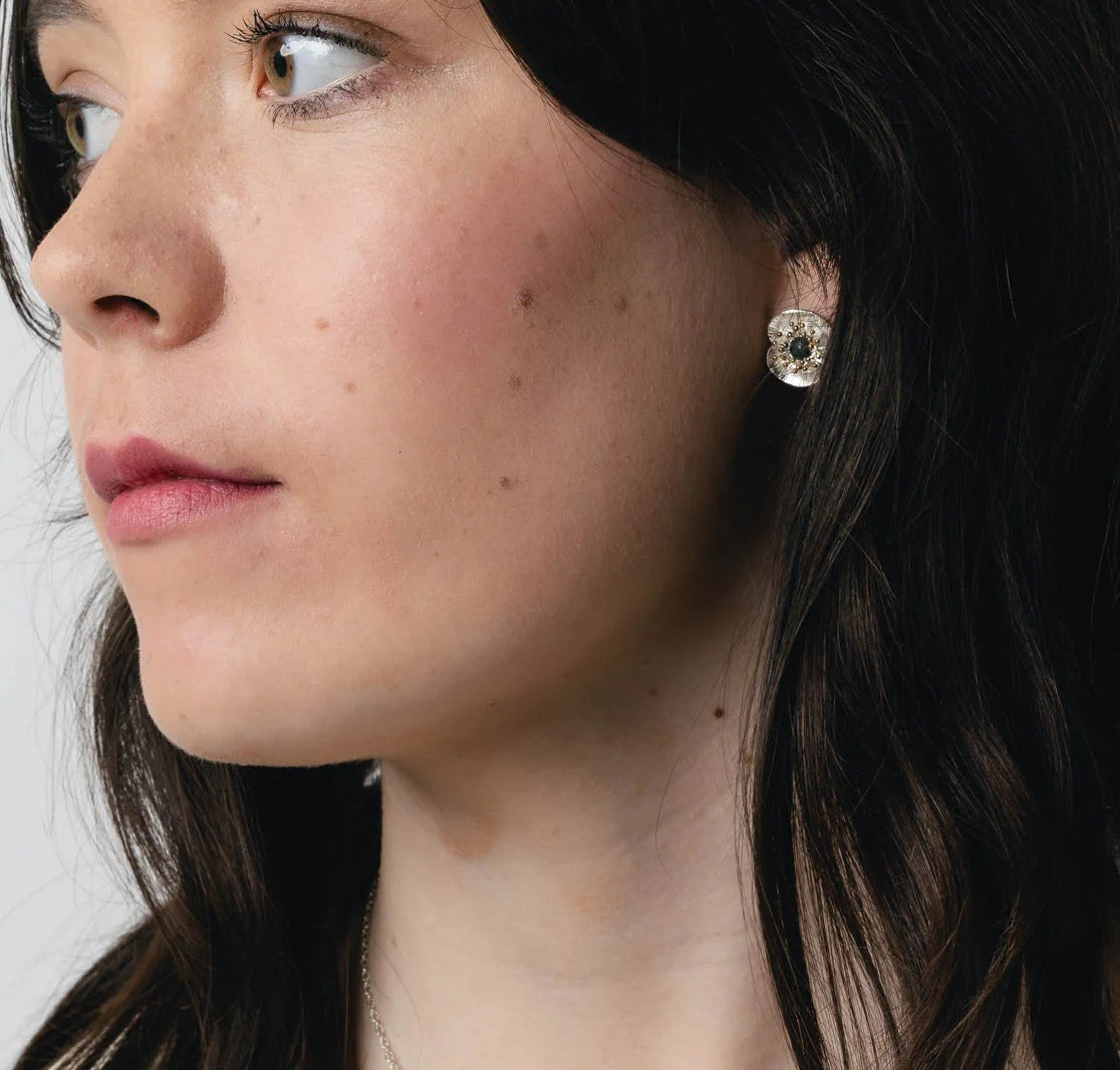 Pair of floral poppy earrings with gold and silver details on a white background