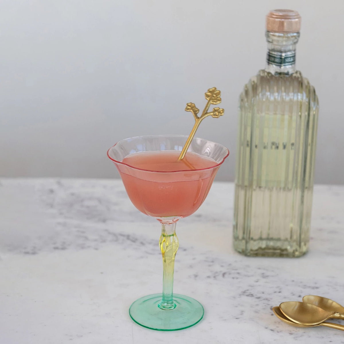 Cocktail in a glass with a bottle and spoon on a marble surface