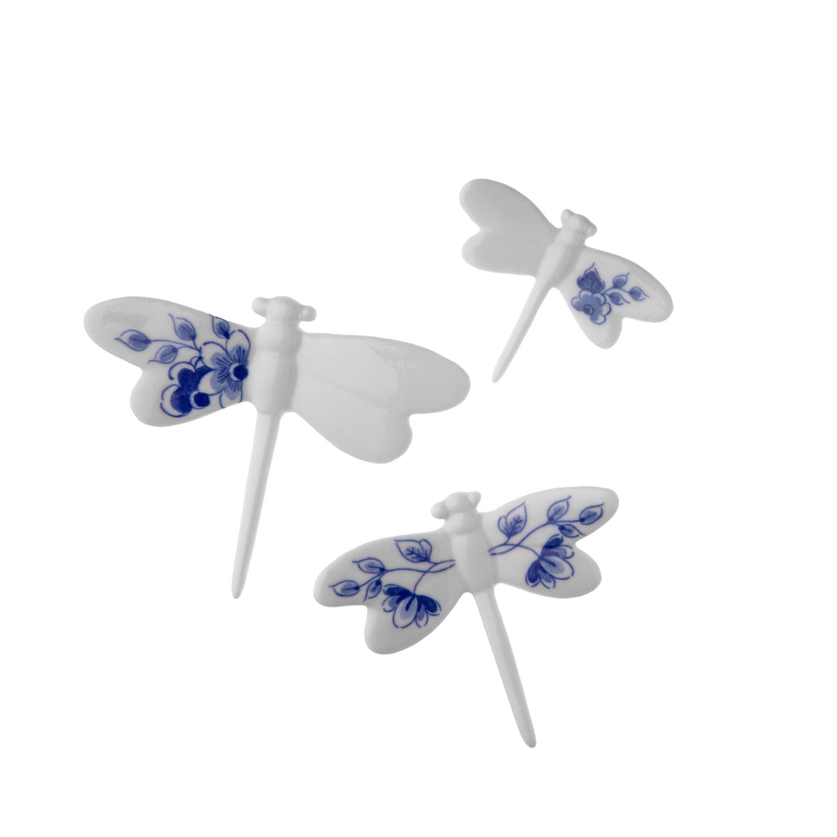 Three white dragonfly-shaped porcelain wall decor figurines with delft blue floral patterns on a white background