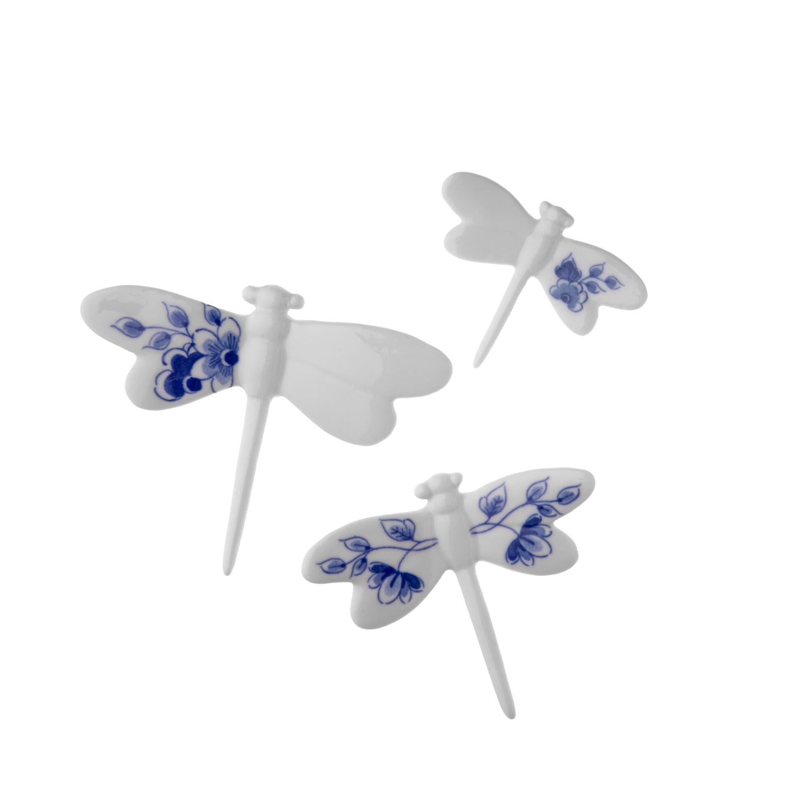 Three white dragonfly-shaped porcelain wall decor figurines with delft blue floral patterns on a white background