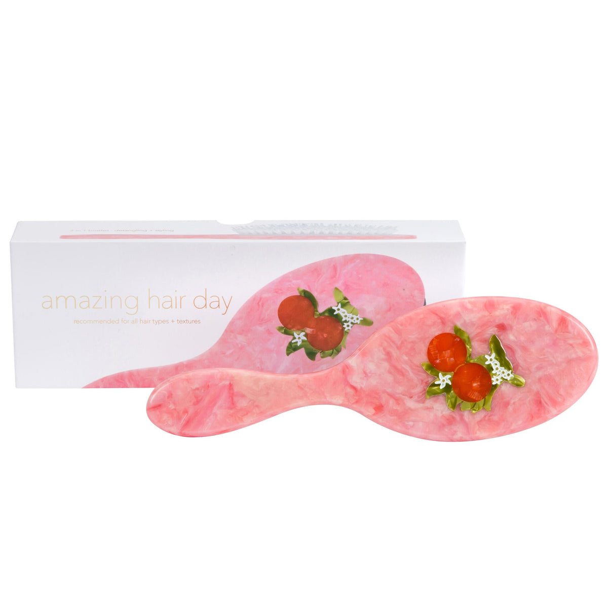 Pink hairbrush with orange and blossom design on a white background