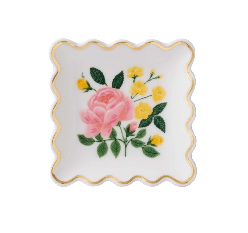 Keep precious jewelry or other small items neatly organized with this rose pattered trinket dish. The design features pink and yellow roses, with verdant green leaves. The porcelain dish has a delightful, scalloped edge which is trimmed with a gold metallic glaze. Material: Porcelain Dimensions: 4" x 4" x 0.76".