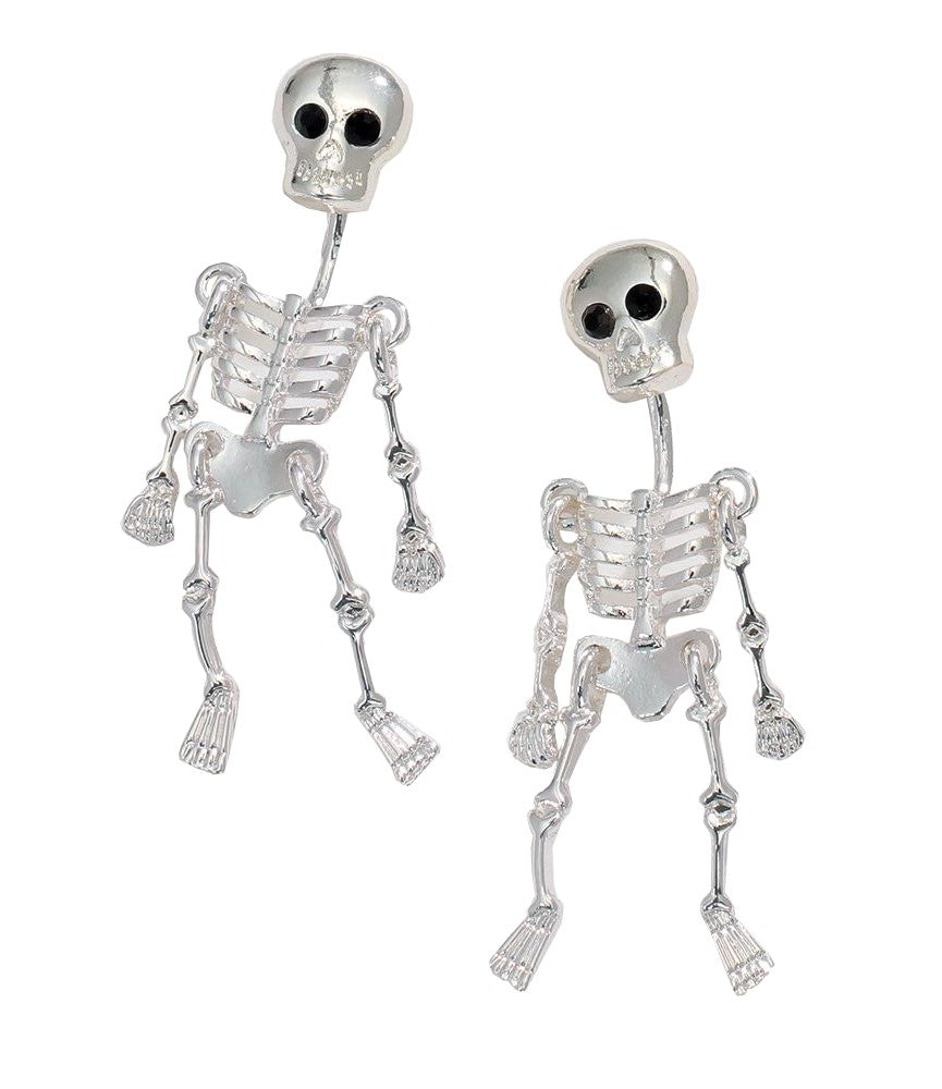 A pair of silver skeleton stud earrings with black eye sockets and small dangling charms, shown on a plain white background.