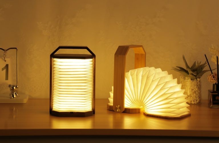 Three illuminated lamps on a wooden surface with a warm glow.