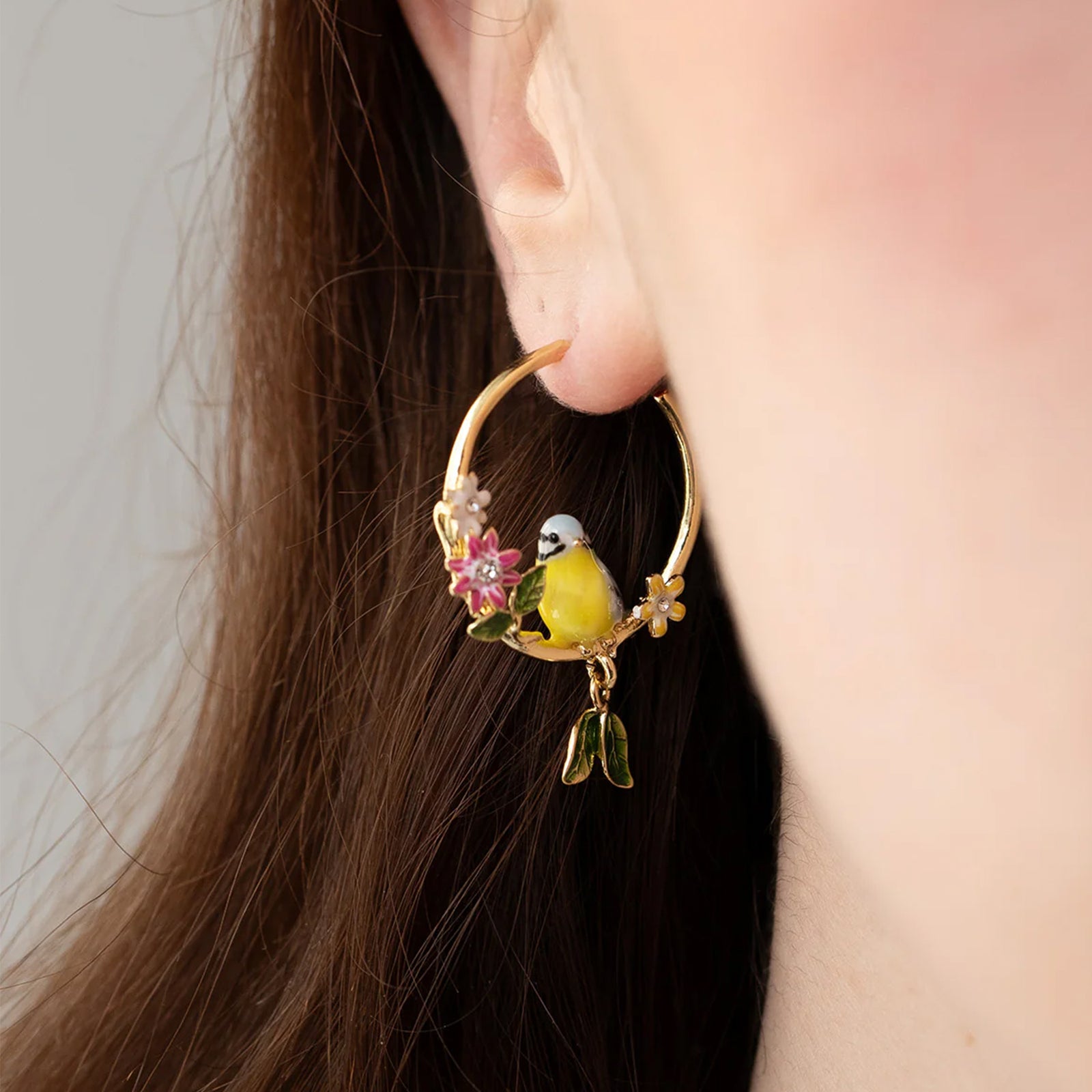 Gold hoop earrings with bird and floral designs on a white background