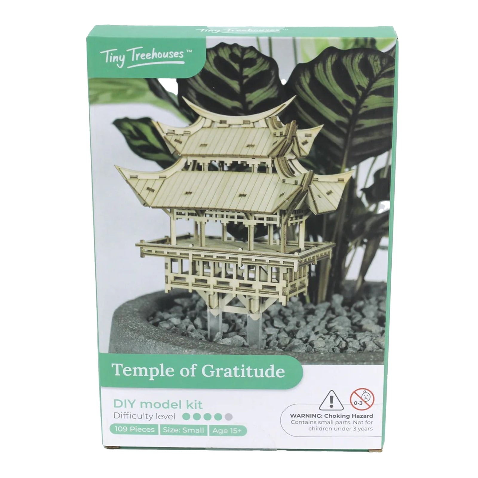 Boxed Temple of Gratitude DIY model kit by Tiny Treehouses with green leaves in the background.
