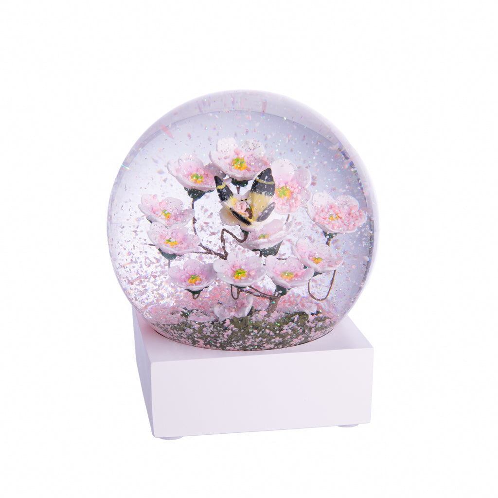 Add the beauty of a sunny spring day to your home year-round with this delightful snow globe. Please note: Please keep your globe out of direct sunlight. The globe is made of glass. It is not a toy and not recommended for younger children. Glass snow globe with wood base Dimensions: 4.5" x 4.5" x 3.5"