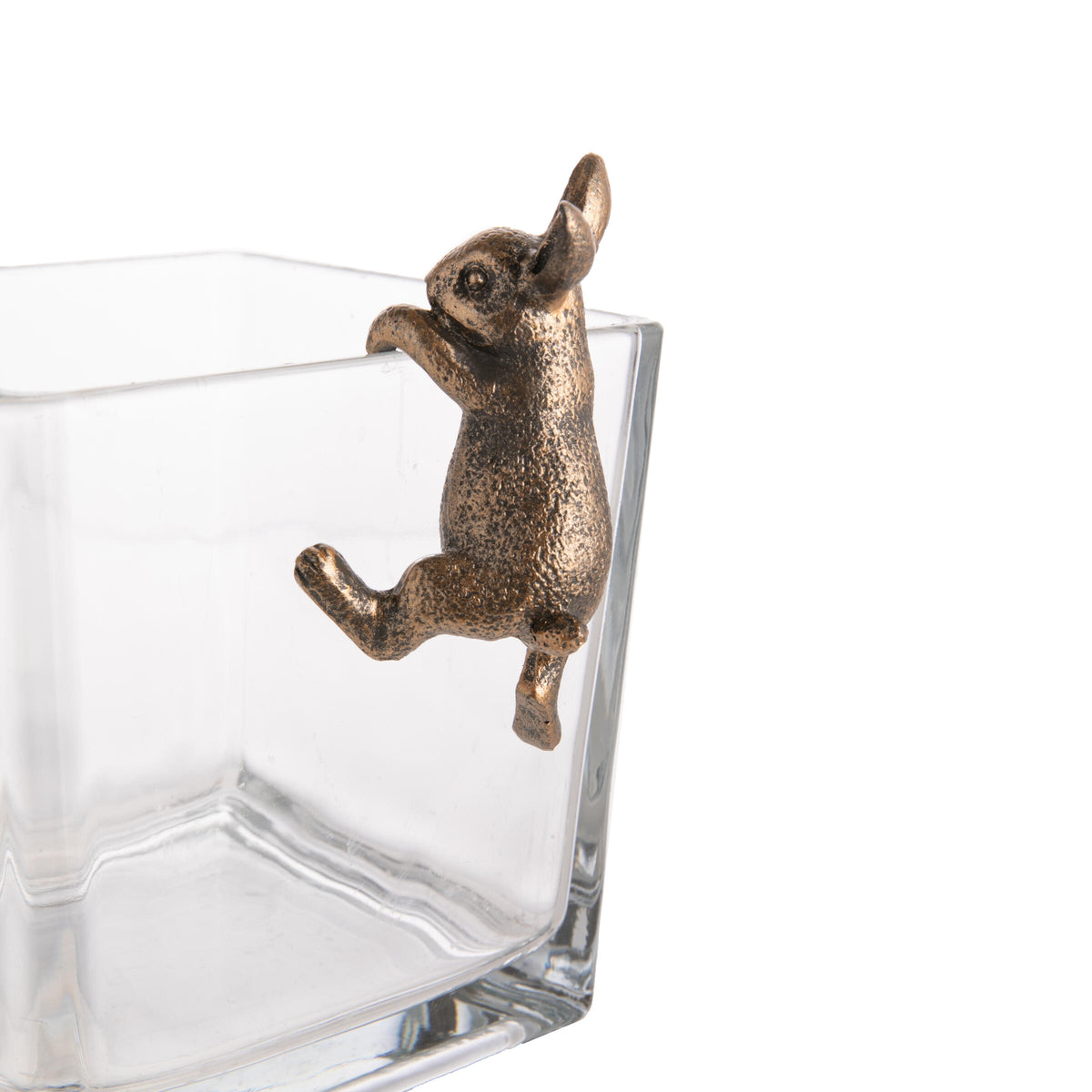 Clear glass container with a bronze rabbit figurine on a white background
