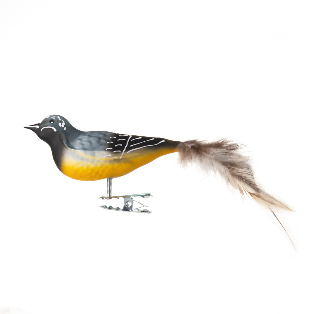 This gray wagtail bird is made from hand-blown glass in a family-owned studio. Its tail is made with real feathers and has a hand-painted finish.