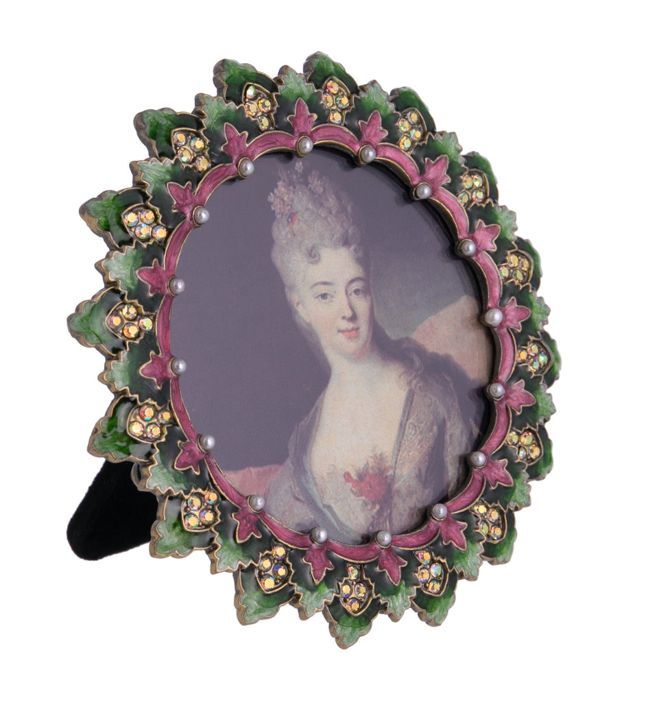 Adorn your shelves or desk with this ornate round picture frame, reminiscent of the Regency era. Around the edge is elaborately decorated green leaves, as well as crystal and pearl detail. Dimensions: approx. 4" x 4" Material: Enamel, crystal detail.