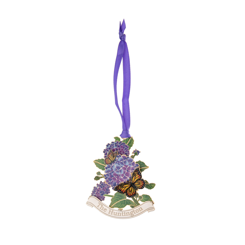 This delightful etched brass ornament is one of a collection of four which depict colorful vignettes from around the Huntington's beloved gardens. From the north vista, two monarch butterflies dart around a pretty lavender-hued Hydrangea. Finished in 24k gold. Dimensions: 2.5" x 2. Exclusive to the Huntington Store.