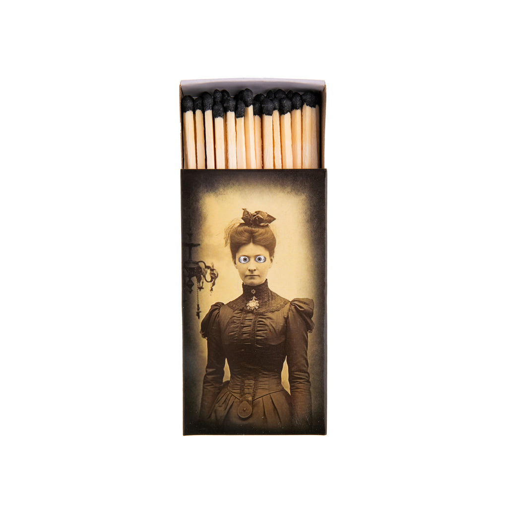 With eerie vintage portraits on either side, this matchbox will look great in your home, whether it is haunted or not. The matches themselves have black tips and the matchbox contains 50 matches. Get ready for some cozy evenings in with lots of candlelight! Dimensions: 4.25" x 2.25" x 0.75" Matchbox with 50 matches